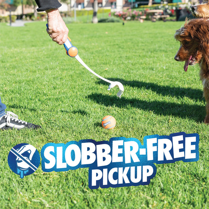 A person uses the Chuckit! Ultra Ball Launcher 18" Medium with a tennis ball to pick up from grass as a brown dog waits, tongue out. "Slobber-Free Pickup" appears on the grass with a drool icon. Brand: Chuckit!.