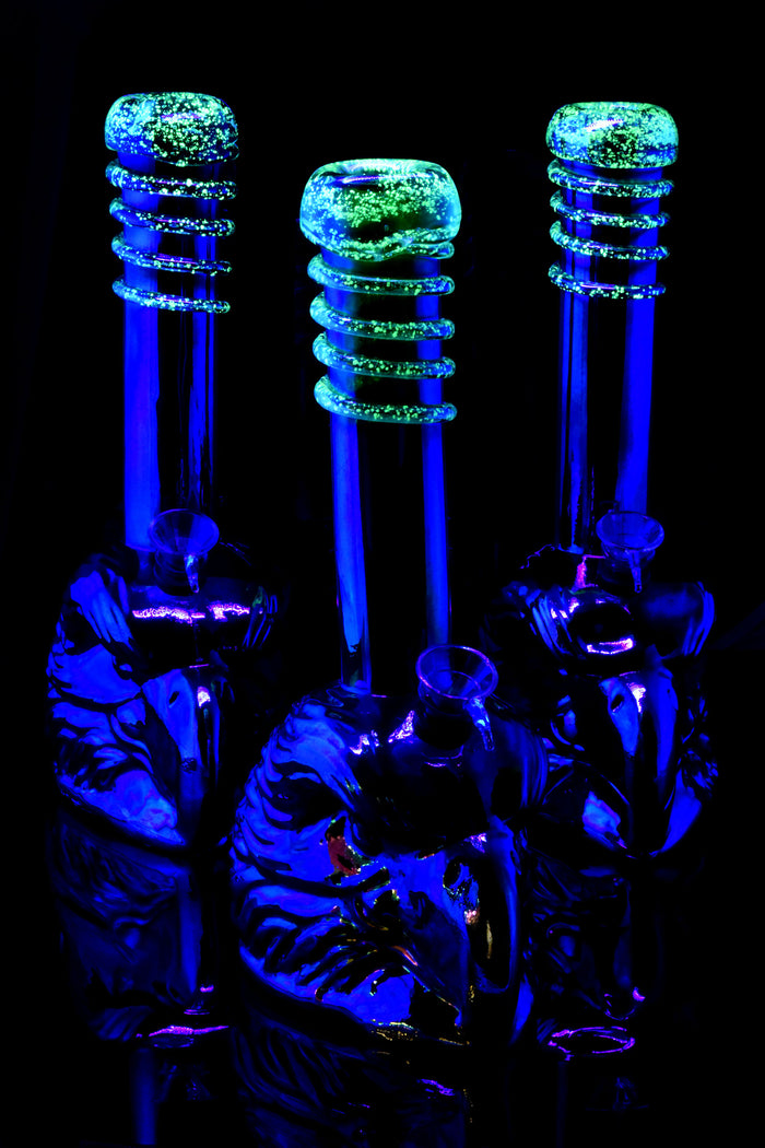 UV-lit glass bong trio with metallic eagle bases and bright green glow-in-the-dark frit neck rings