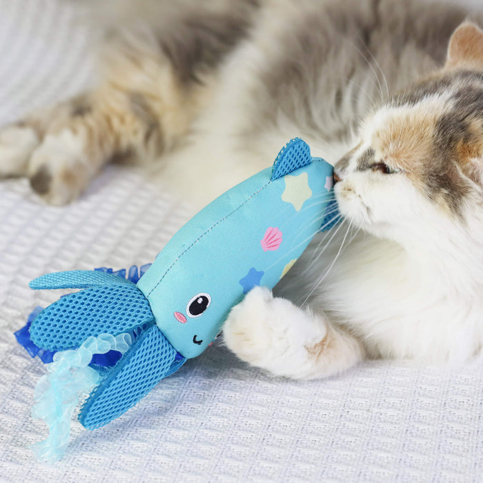 A fluffy cat lies on a white textured blanket, snuggling the Quirky Kitty Octopurr Kicker – an ocean-themed catnip kicker toy by Quirky Kitty shaped like an octopus with fun fabric details.