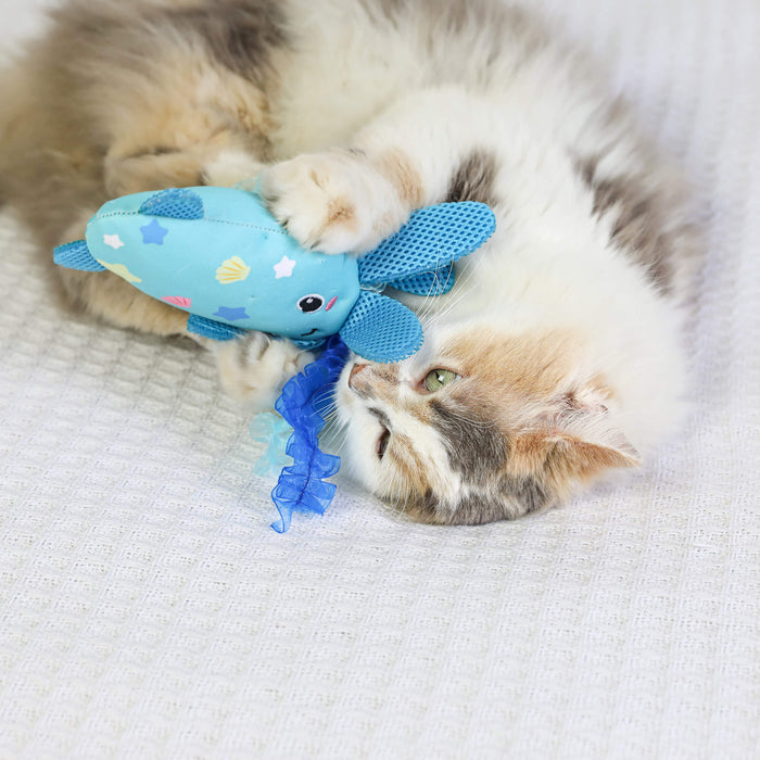 A fluffy cat lounges on a white textured surface, playfully hugging and biting the Quirky Kitty Octopurr Kicker – an ocean-themed catnip toy from Quirky Kitty.
