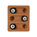 The Quirky Kitty Sushi Bento Box Puzzle Cat Toy features a brown wooden board with three sliding tracks and four black circular pieces, each adorned with a cupcake design. Two tracks contain two pieces, while one track is left empty to challenge feline cognition.