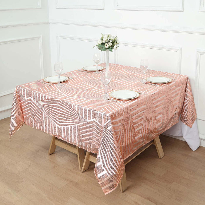 Rose gold geometric tablecloth draping a wooden table set for dinner.